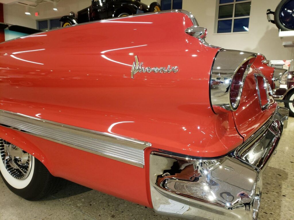 A vibrant 1960 Dodge Dart Phoenix Convertible gleams under soft lighting. Its bold fins, chrome trim, and open-top design scream classic American style.